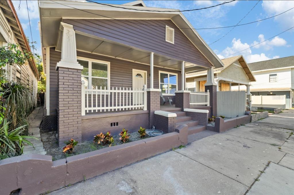 A purple bungalow with a front porch, brick pillars, and a low concrete retaining wall — 2912 N 16TH STREET, TAMPA, FL