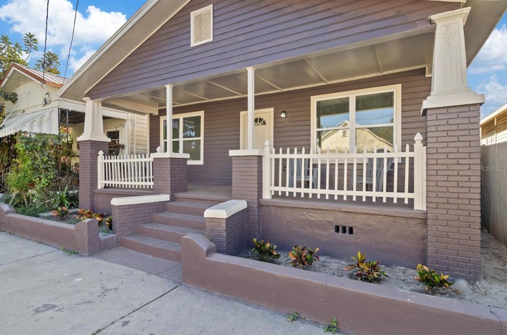 A purple house with a front porch, white picket railing, and brick support columns — 2912 N 16TH STREET, TAMPA, FL