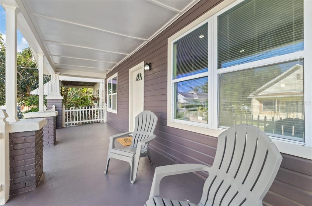 A covered front porch features gray siding, two plastic chairs, and brick support columns — 2912 N 16TH STREET, TAMPA, FL