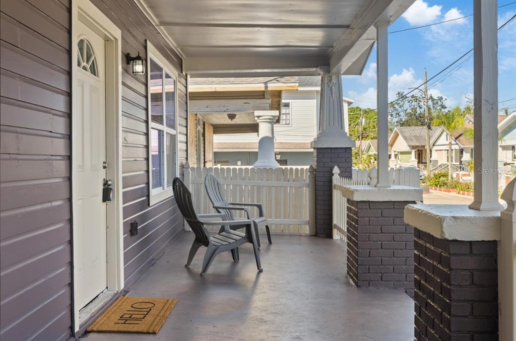 A covered front porch features two gray chairs, a white picket fence, and brick columns — 2912 N 16TH STREET, TAMPA, FL