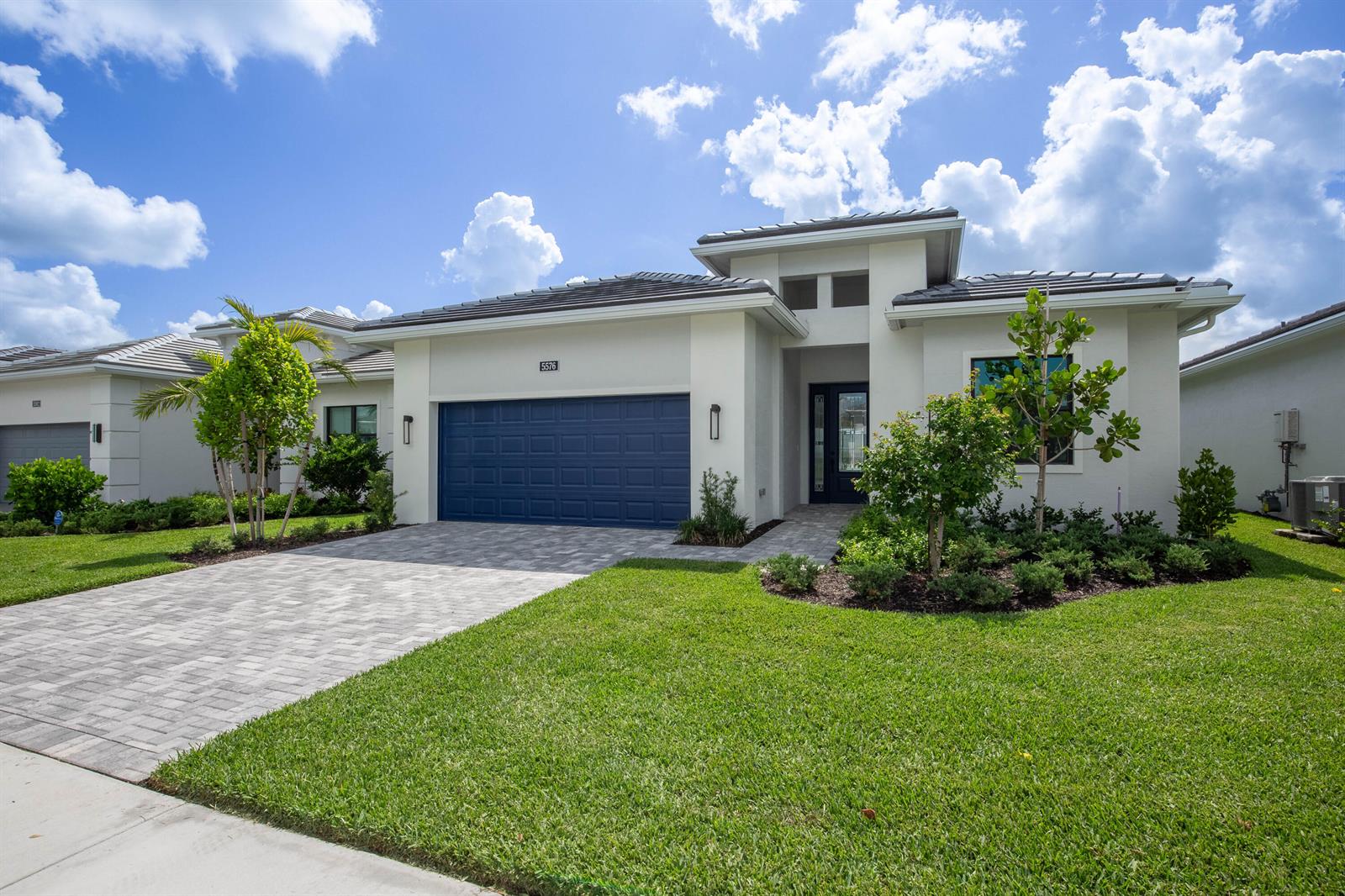 A single-story house with a blue garage door, paved driveway, and landscaped front yard — 5576 Captiva Lane, FL 33470, FL