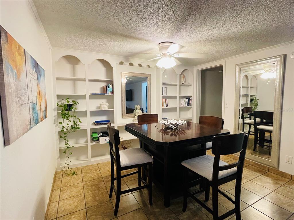 A dining room features a square table, four chairs, built-in shelving, and a large wall mirror — 2490 SW 14TH DR UNIT 29, GAINESVILLE, FL