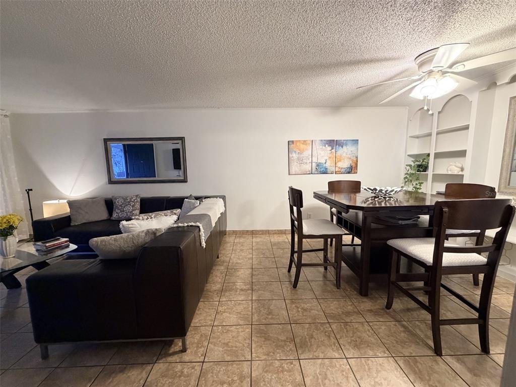 A living and dining area features tile flooring, a dark leather sofa, and wooden furniture — 2490 SW 14TH DR UNIT 29, GAINESVILLE, FL