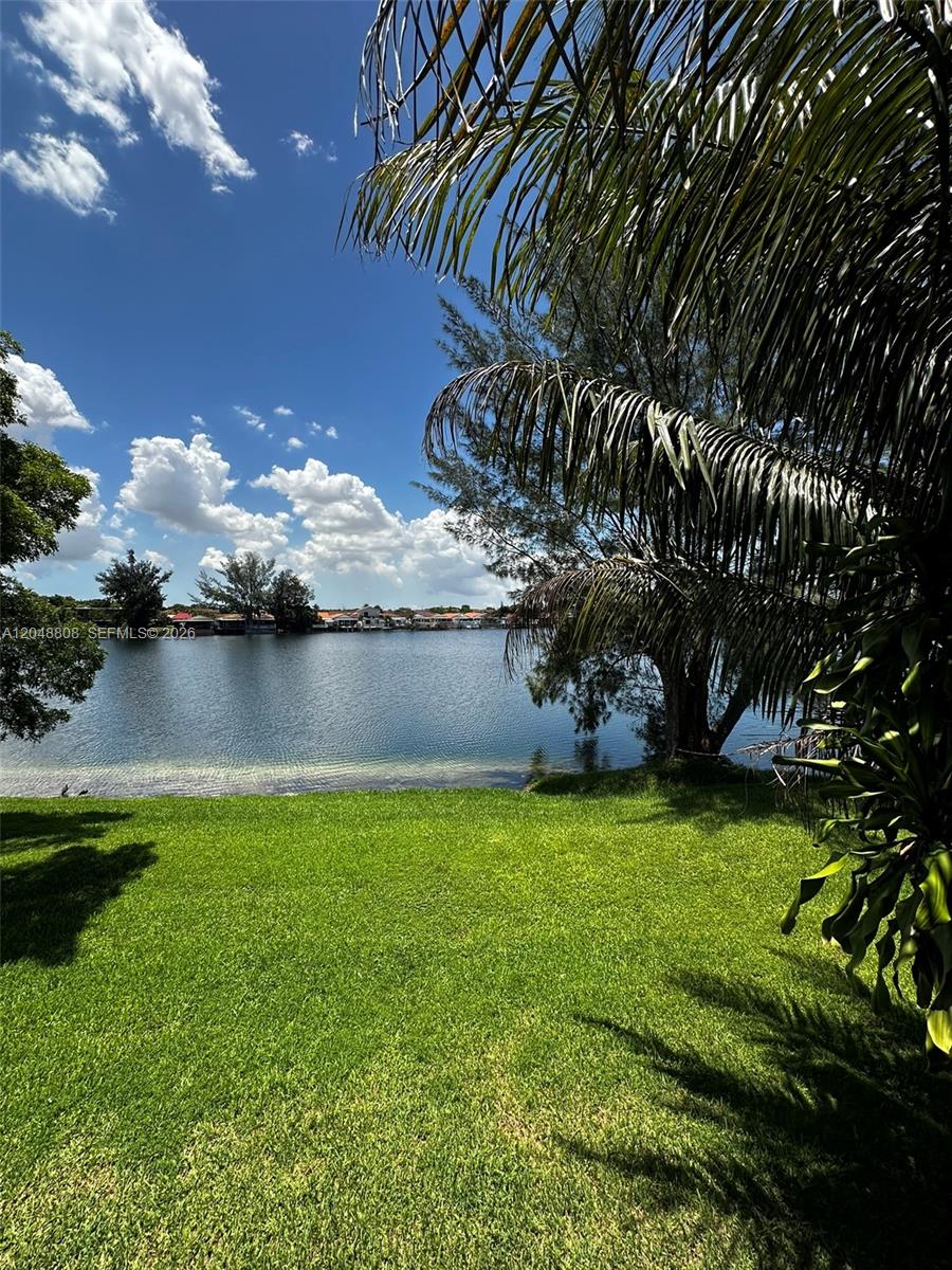A grassy lawn leads to a lake with houses visible on the distant shore — 2540 W 67th Pl # 28, Hialeah FL 33016, HIALEAH, FL