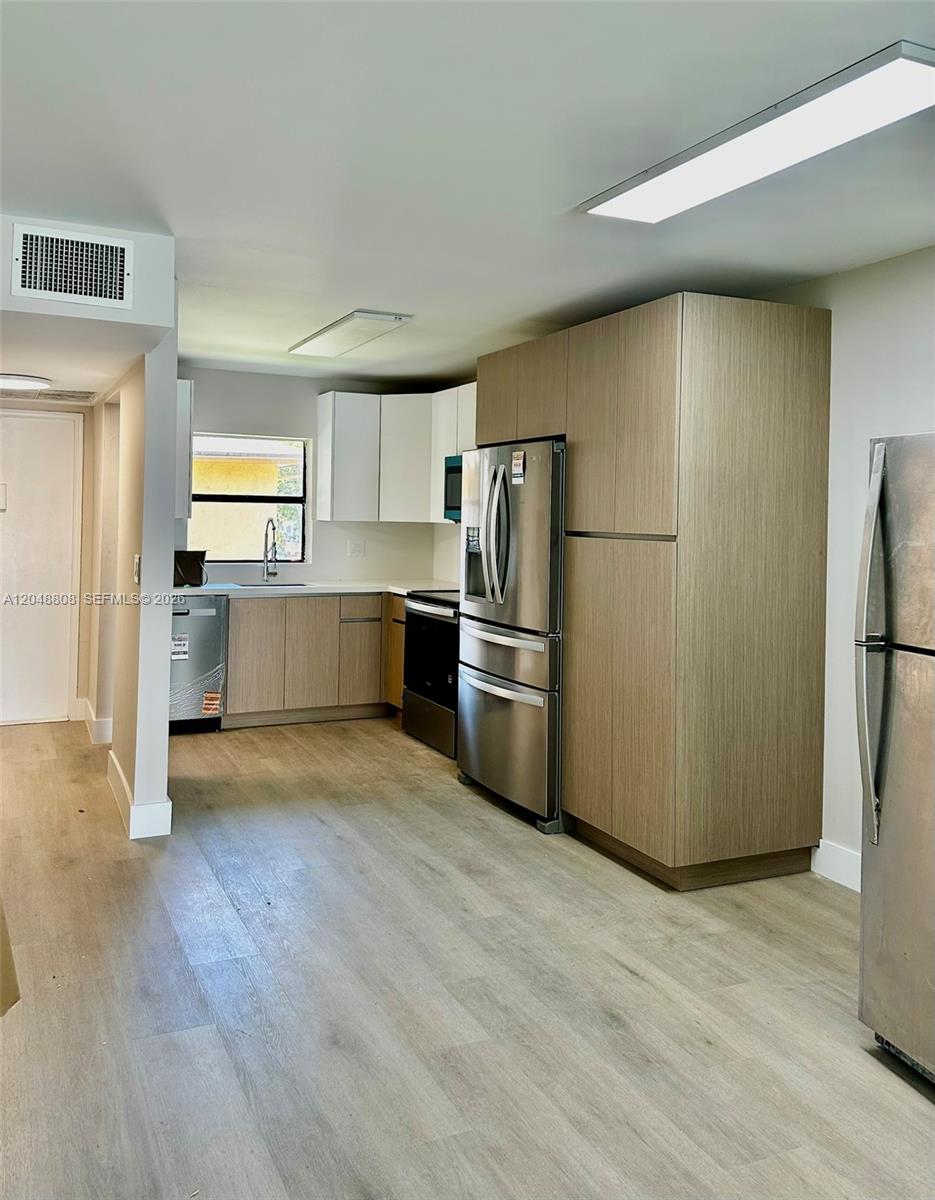 A kitchen features light wood-look flooring, stainless steel appliances, and a mix of cabinet finishes — 2540 W 67th Pl # 28, Hialeah FL 33016, HIALEAH, FL