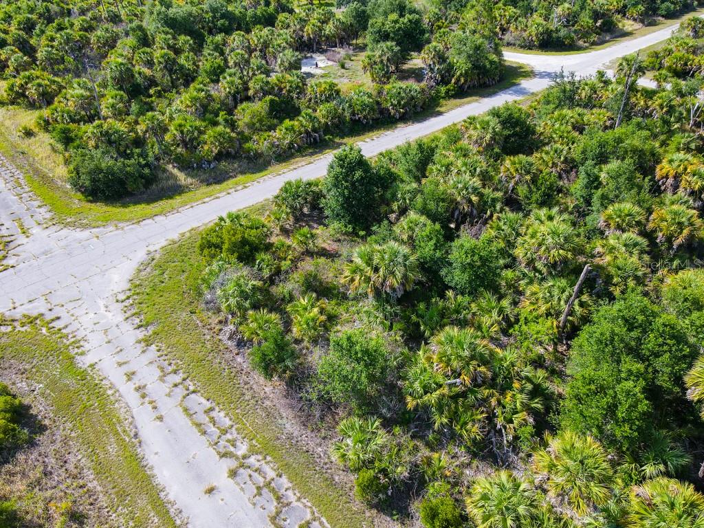An aerial view shows a vacant, wooded lot situated at the corner of two paved roads — FIREBIRD ROAD, NORTH PORT, FL