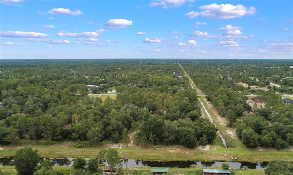 An aerial view shows a wooded landscape with a canal and a drainage ditch — Lot 1120 QUARTERLY PARKWAY, ORLANDO, FL