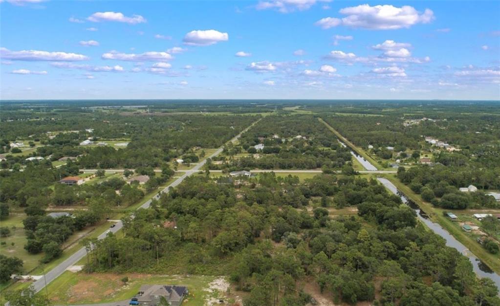 An aerial view shows a rural residential area with scattered houses, wooded lots, and roads — Lot 1120 QUARTERLY PARKWAY, ORLANDO, FL