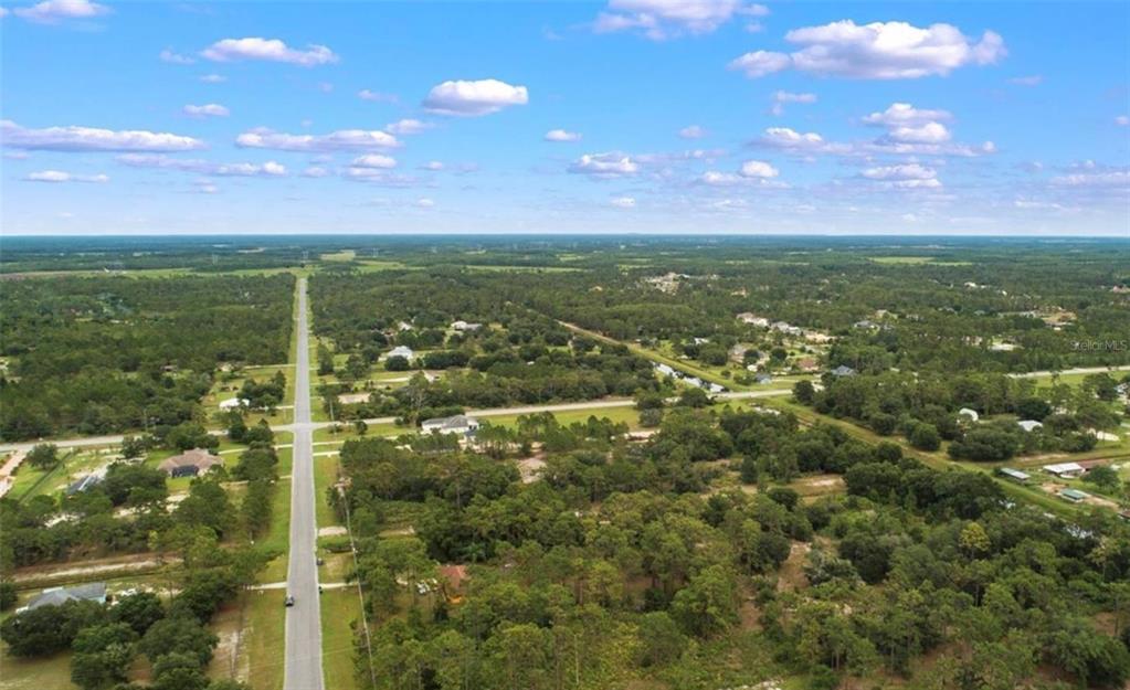An aerial view shows a paved road running through a rural, wooded residential area — Lot 1120 QUARTERLY PARKWAY, ORLANDO, FL