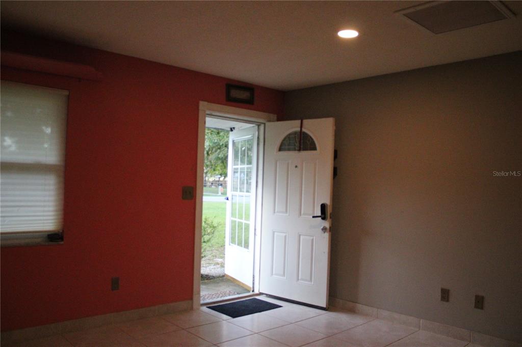 An interior room with tile flooring, a red wall, and an open front door — 5920 NW 62ND PLACE, OCALA, FL