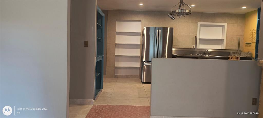 A kitchen features stainless steel appliances, open shelving, tile flooring, and a gray half wall — 5920 NW 62ND PLACE, OCALA, FL