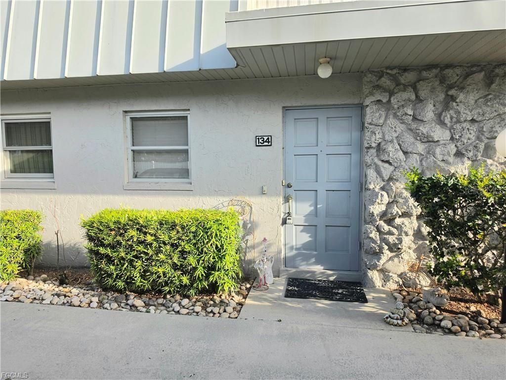 A light blue front door with the number 134 sits beside a stone-faced wall — 6777 WINKLER ROAD UNIT 134, FORT MYERS, FL