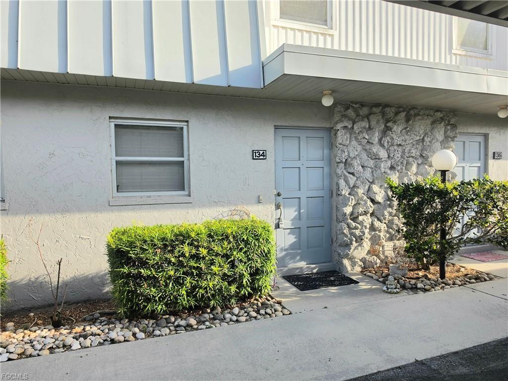 The exterior of a residential building features a light blue door marked 134 — 6777 WINKLER ROAD UNIT 134, FORT MYERS, FL