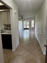 A view from a tiled hallway looking into a kitchen and a living area beyond — 3100 S SEMORAN BOULEVARD UNIT 11, ORLANDO, FL