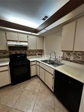 A kitchen features white cabinets, black appliances, tile flooring, and a tiled backsplash — 3100 S SEMORAN BOULEVARD UNIT 11, ORLANDO, FL