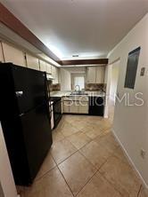A kitchen features a black refrigerator, light-colored cabinets, a double sink, and tiled flooring — 3100 S SEMORAN BOULEVARD UNIT 11, ORLANDO, FL