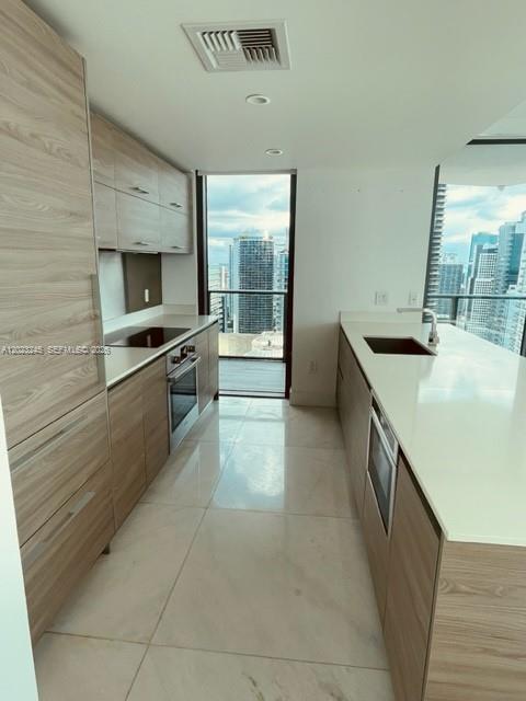 A modern kitchen features light wood cabinetry, white countertops, and a balcony with city views — 1300 S Miami Ave # 4001, Miami FL 33130, MIAMI, FL