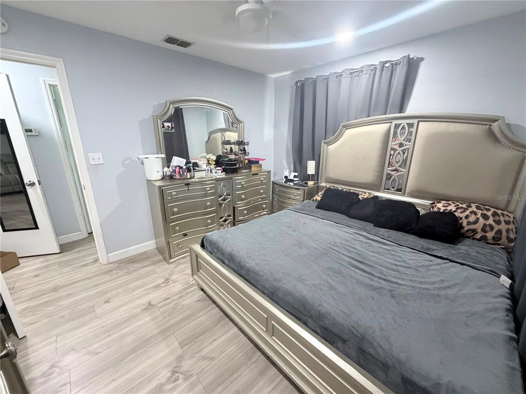 A bedroom features a metallic-finish bed frame, matching dresser with mirror, and light wood flooring — 7281 SE 120TH STREET UNIT 1, BELLEVIEW, FL