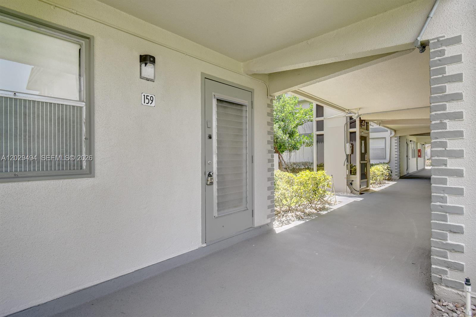 An exterior view shows a covered walkway leading to a door numbered 159 — 159 Brittany D # 159, Delray Beach FL 33446, DELRAY BEACH, FL