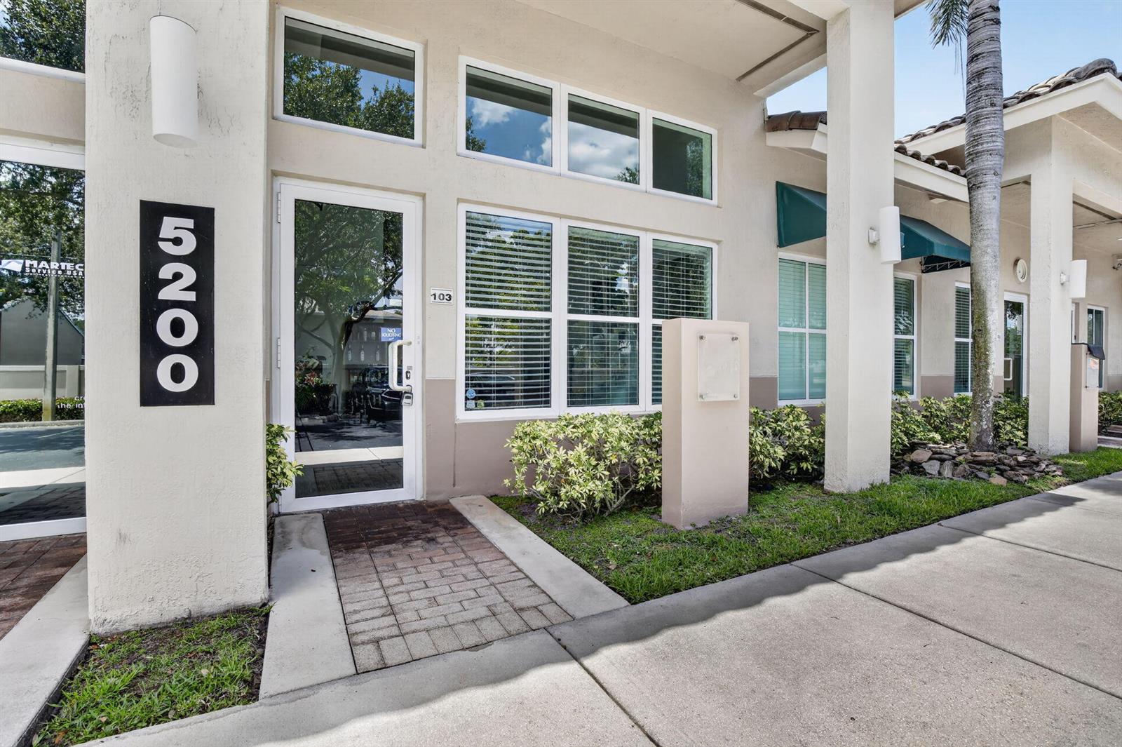 The exterior of a commercial building features a glass door, large windows, and address numbers — 5200 S University Drive # 103a, Davie FL 33328, DAVIE, FL