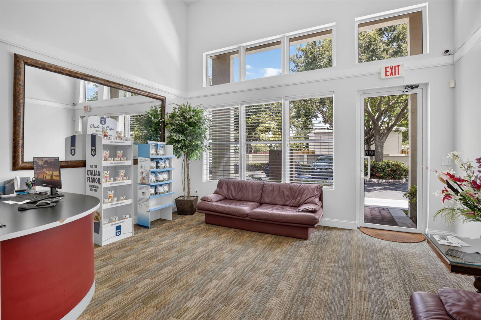 A bright office lobby features a red reception desk, a leather sofa, and large windows — 5200 S University Drive # 103a, Davie FL 33328, DAVIE, FL