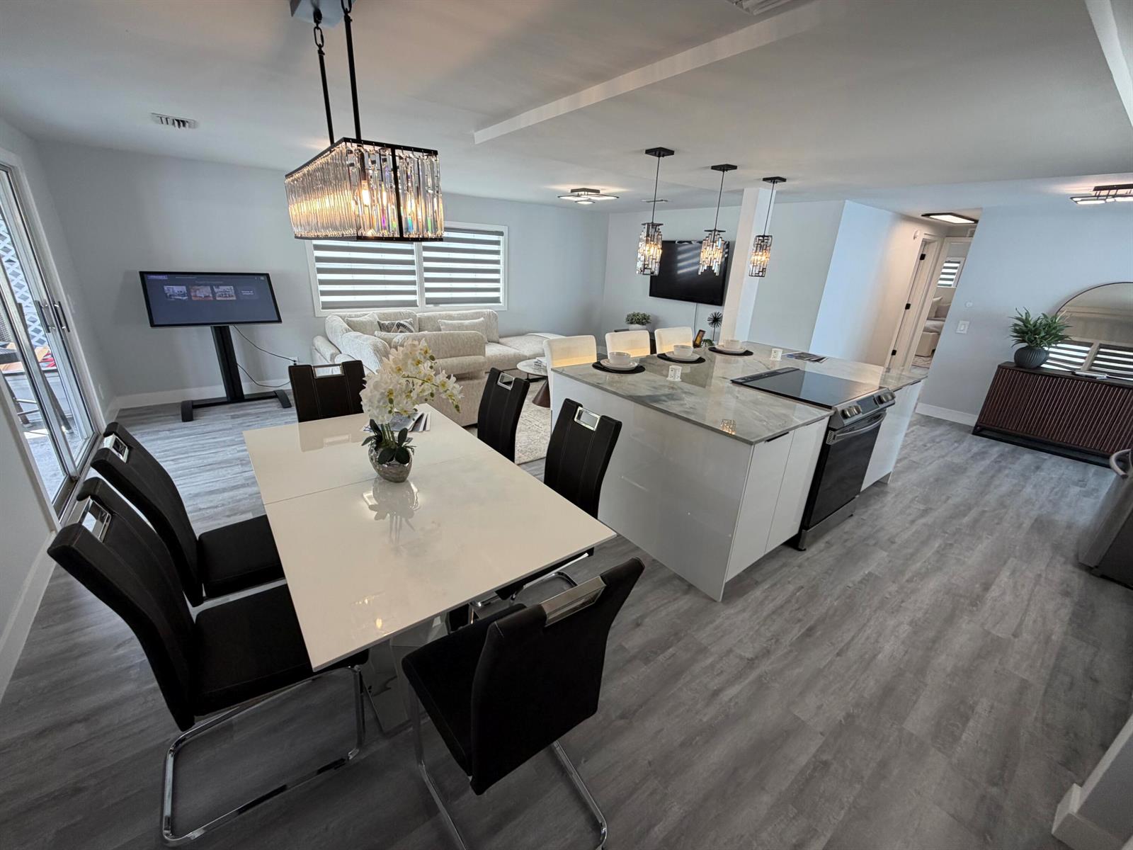 A modern open-concept dining and kitchen area features a white table, island, and gray flooring — 6600 NW 29th Court, Margate FL 33063, MARGATE, FL