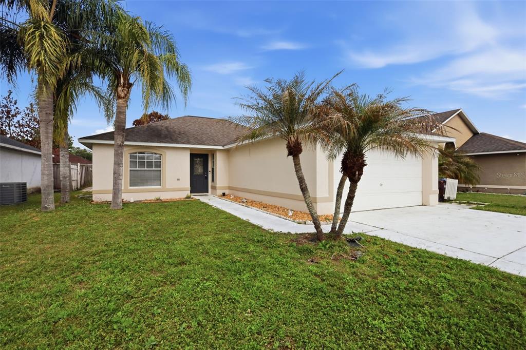 A single-story house with a beige stucco exterior, a two-car garage, and two palm trees — 2943 CIALELLA PASS, ST CLOUD, FL