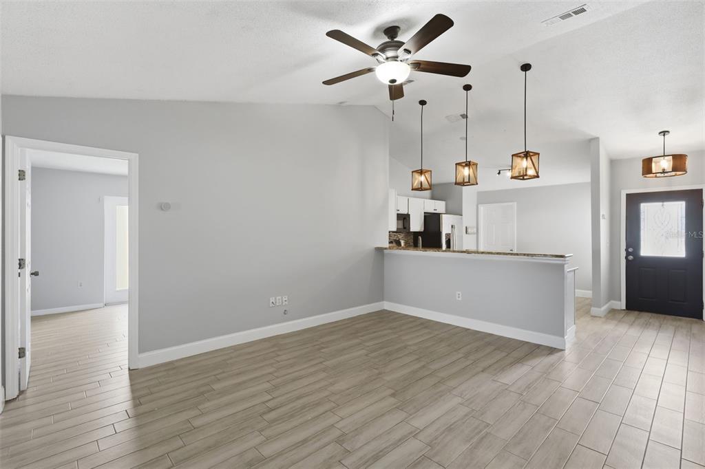 A living area with light gray walls, wood-look tile flooring, a ceiling fan, and pendant lights — 2943 CIALELLA PASS, ST CLOUD, FL