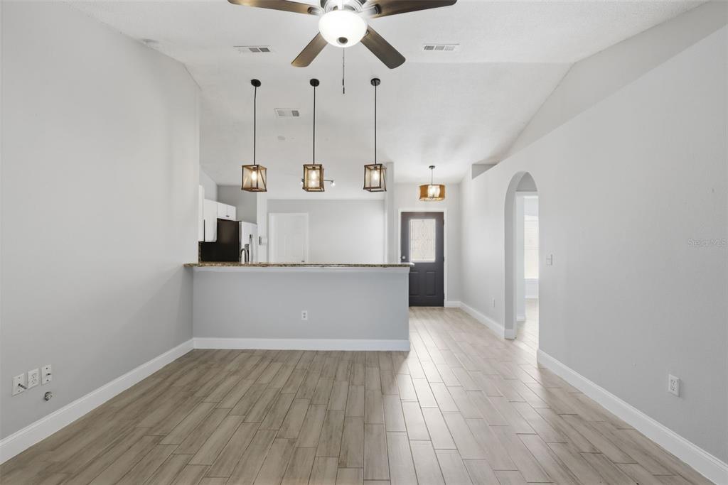 A room with light wood-look tile flooring, a breakfast bar, and three hanging pendant lights — 2943 CIALELLA PASS, ST CLOUD, FL