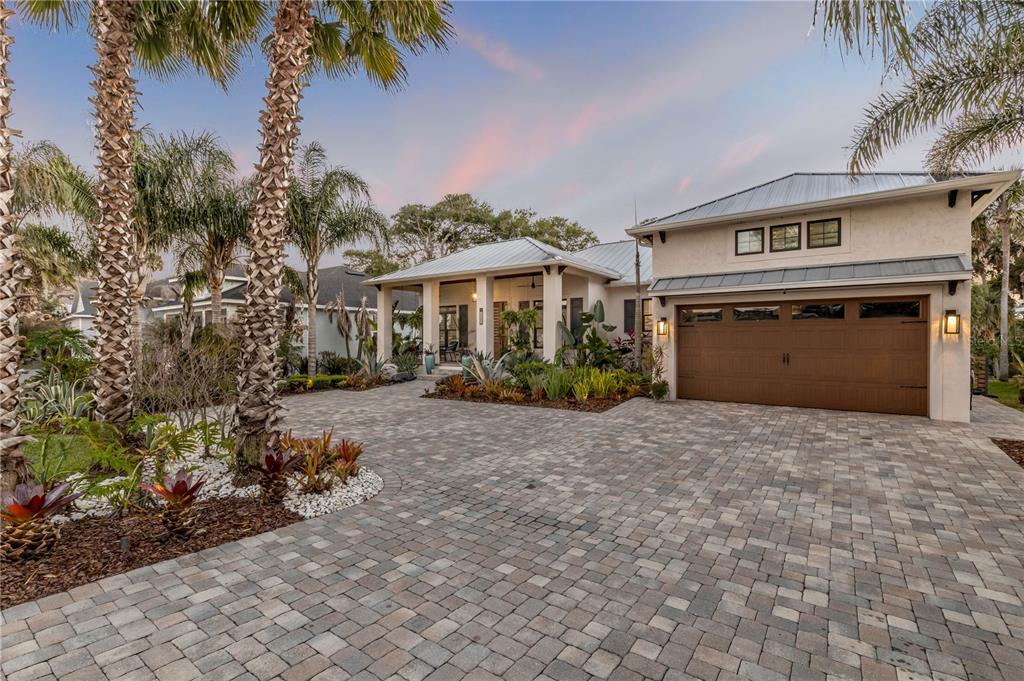 A single-story house with a metal roof, a paved driveway, and a covered front porch — 1502 SAXON DRIVE, NEW SMYRNA BEACH, FL