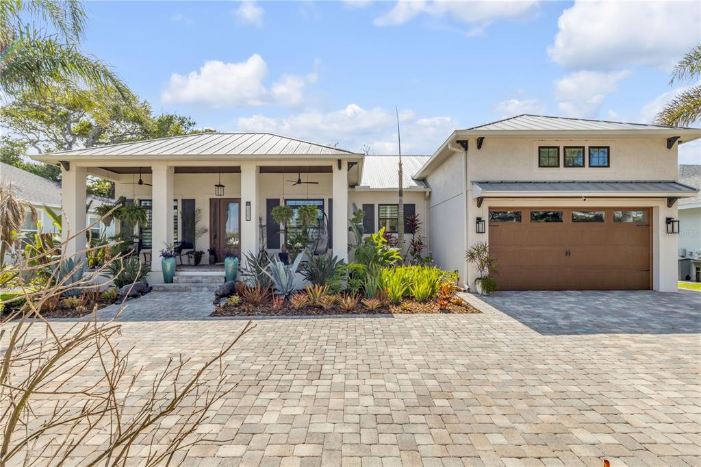 A single-story house with a metal roof, a paved driveway, and palm trees in the yard — 1502 SAXON DRIVE, NEW SMYRNA BEACH, FL