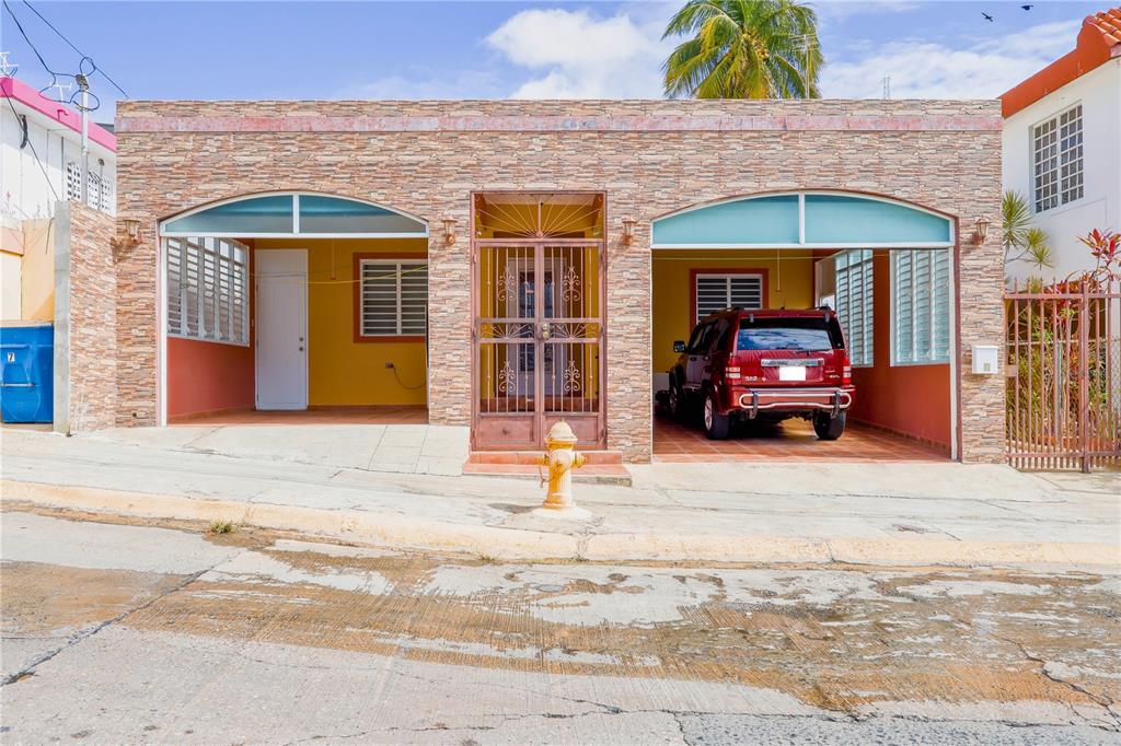 A single-story house with a stone facade, two open garages, and a central gated entrance — 7 CALLE OPALO, AGUADILLA, PR