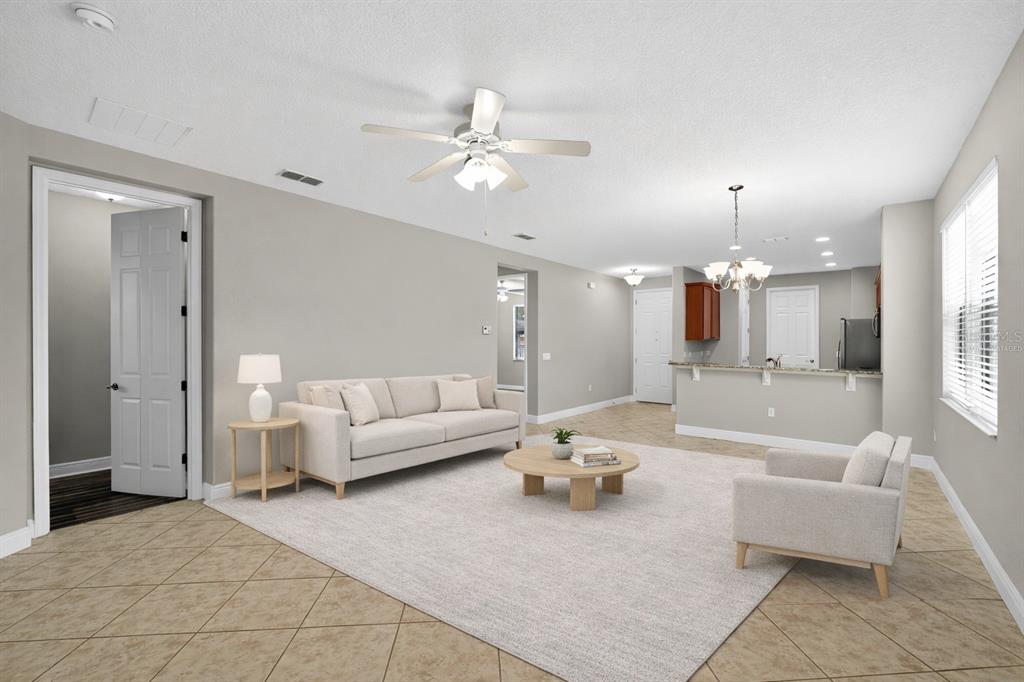 A living room with tile floors, a beige sofa, an armchair, and an open kitchen — 507 PRESIDO PARK PLACE, KISSIMMEE, FL