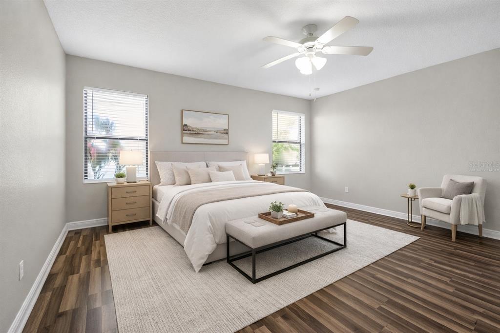 A bedroom features wood-look flooring, a bed with a bench, two windows, and a ceiling fan — 507 PRESIDO PARK PLACE, KISSIMMEE, FL
