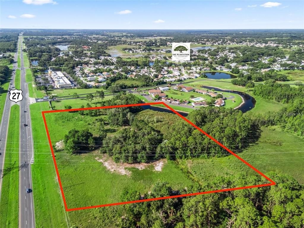 An aerial view shows a vacant, rectangular plot of land bordered by a highway — US HIGHWAY 27, LEESBURG, FL