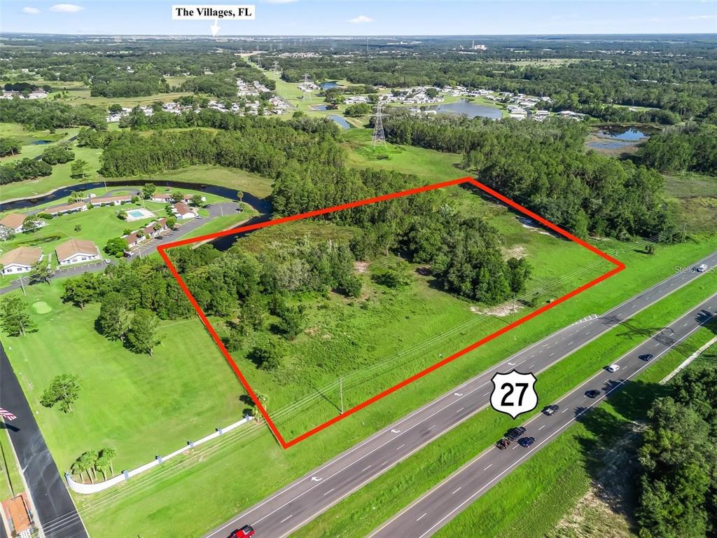 An aerial view shows a vacant, rectangular plot of land bordering a highway — US HIGHWAY 27, LEESBURG, FL
