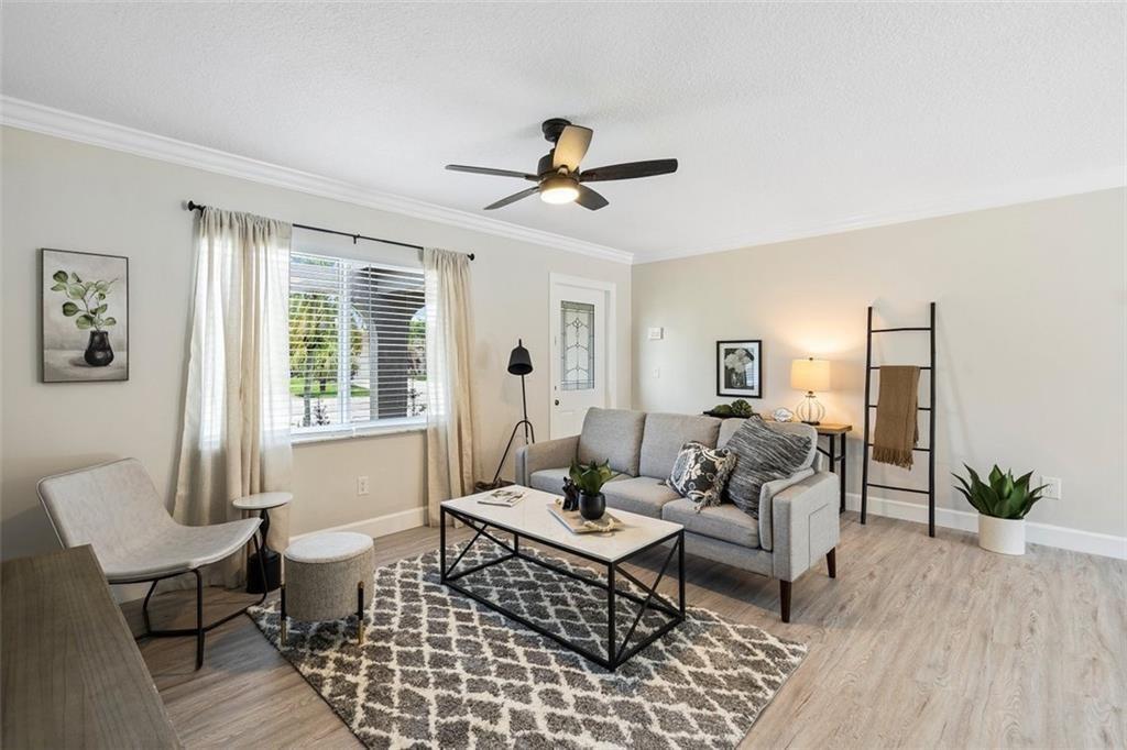 A living room features a grey sofa, patterned area rug, ceiling fan, and light flooring — 10884 Gantry Street, Boca Raton FL 33428, BOCA RATON, FL
