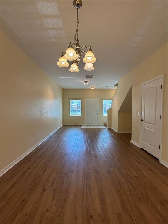 An open living area features light-colored walls, wood-look flooring, and a central chandelier — 4154 WINDING VINE DRIVE, LAKELAND, FL