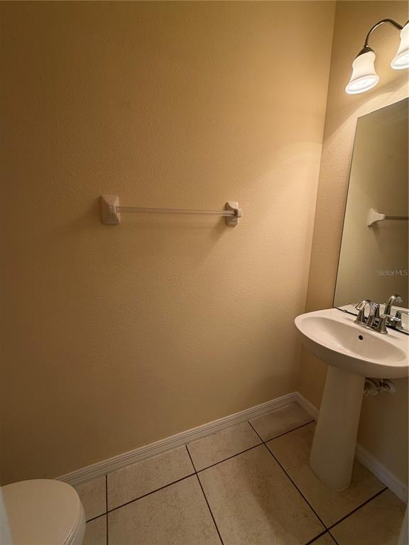 A half bathroom features a pedestal sink, a wall-mounted towel bar, and tile flooring — 4154 WINDING VINE DRIVE, LAKELAND, FL