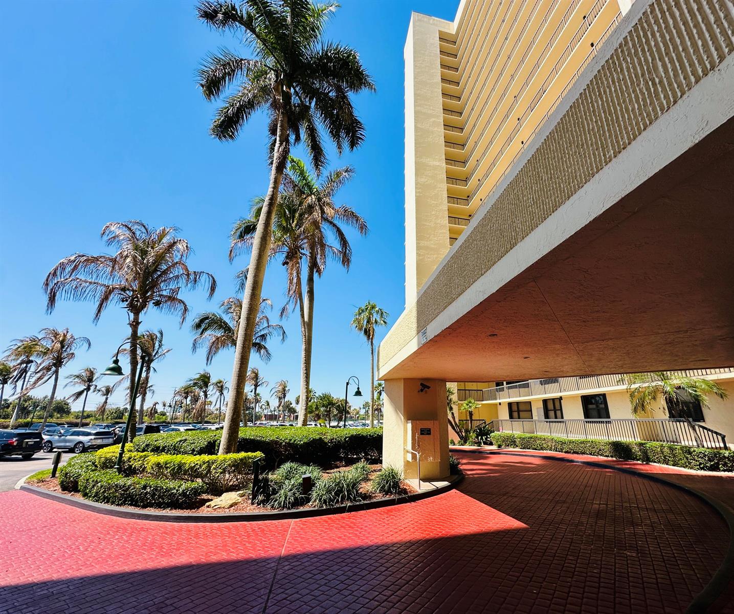 A tall apartment building with a red brick driveway and palm trees under a blue sky — 9500 S Ocean Drive # 108, Jensen Beach FL 34957, JENSEN BEACH, FL