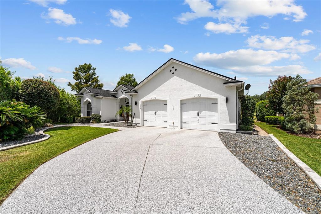 A backyard view of a house with a screened-in pool and a covered patio area — 714 CIMARRON AVENUE, THE VILLAGES, FL
