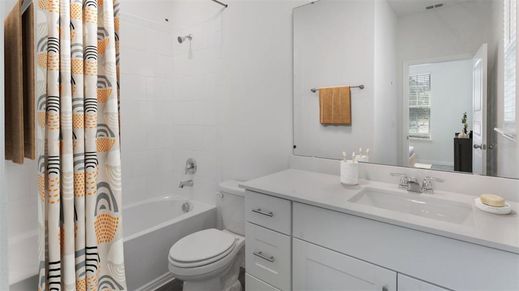 A bathroom features a white vanity, a toilet, and a shower-tub combo with patterned curtains — 16834 HOBE SOUND COURT, WINTER GARDEN, FL