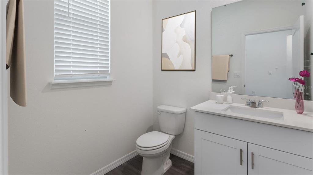 A bathroom features a white vanity, a toilet, a window with blinds, and wall art — 16834 HOBE SOUND COURT, WINTER GARDEN, FL