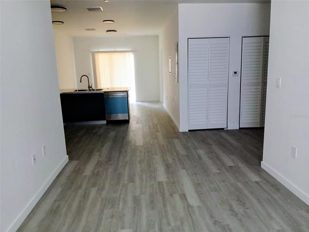 A kitchen with a dark island and light wood-look flooring leads to a sliding door — 1583 NW 29TH ROAD UNIT 2, GAINESVILLE, FL