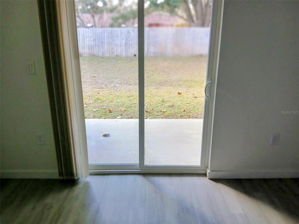 A sliding glass door opens from a room with light wood-look flooring to a patio — 1583 NW 29TH ROAD UNIT 2, GAINESVILLE, FL