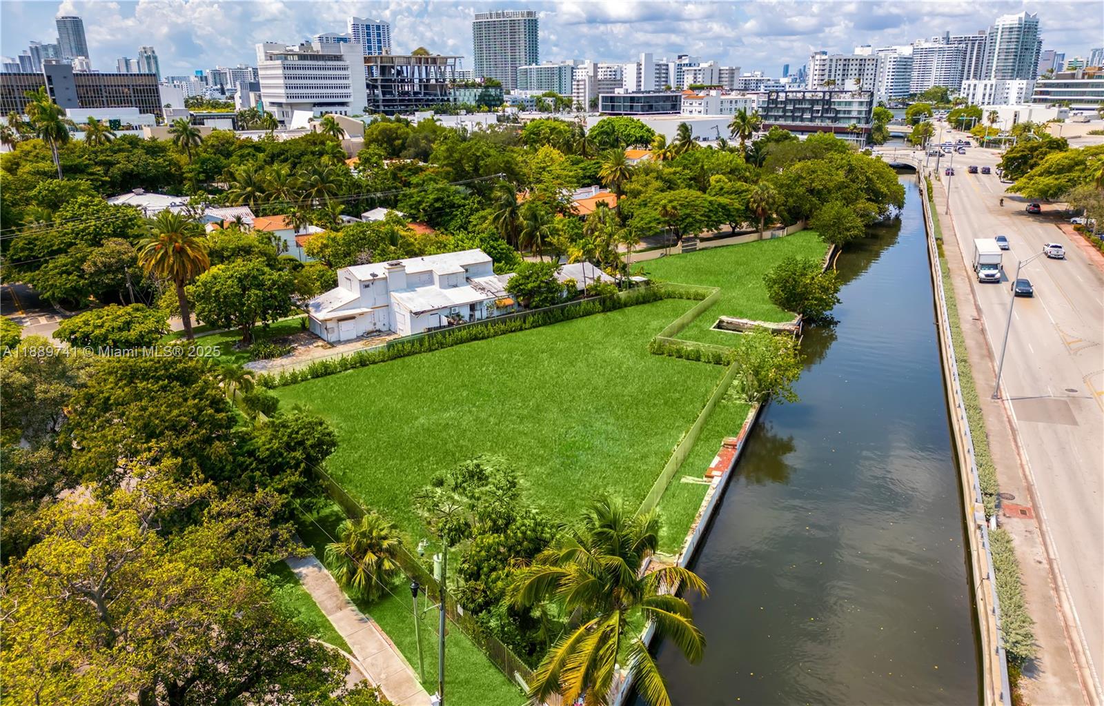 An aerial view shows a vacant grassy lot next to a canal and a road — 18th st Michigan Ave, Miami Beach FL 33139, MIAMI BEACH, FL