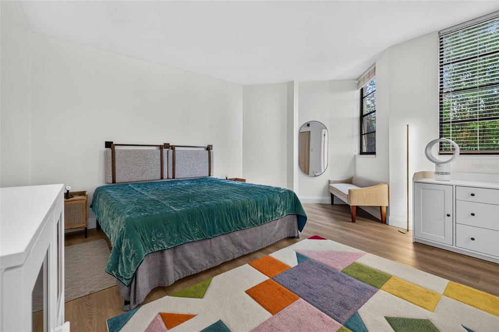 A bedroom features a teal velvet bed, a colorful geometric rug, and a white dresser — 602 LIME AVENUE UNIT 101, CLEARWATER, FL
