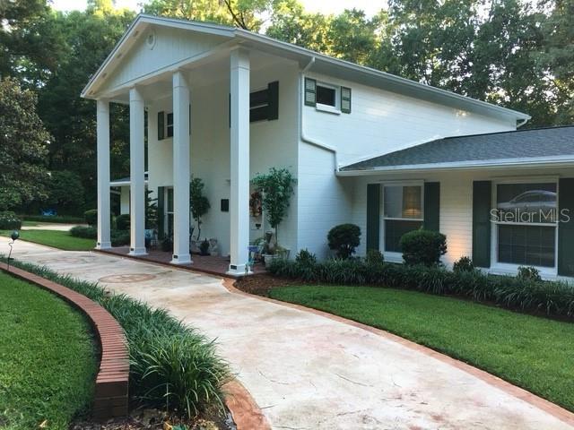 A two-story white house with a large front porch and columns stands near a driveway — 2006 NW 23RD STREET, GAINESVILLE, FL