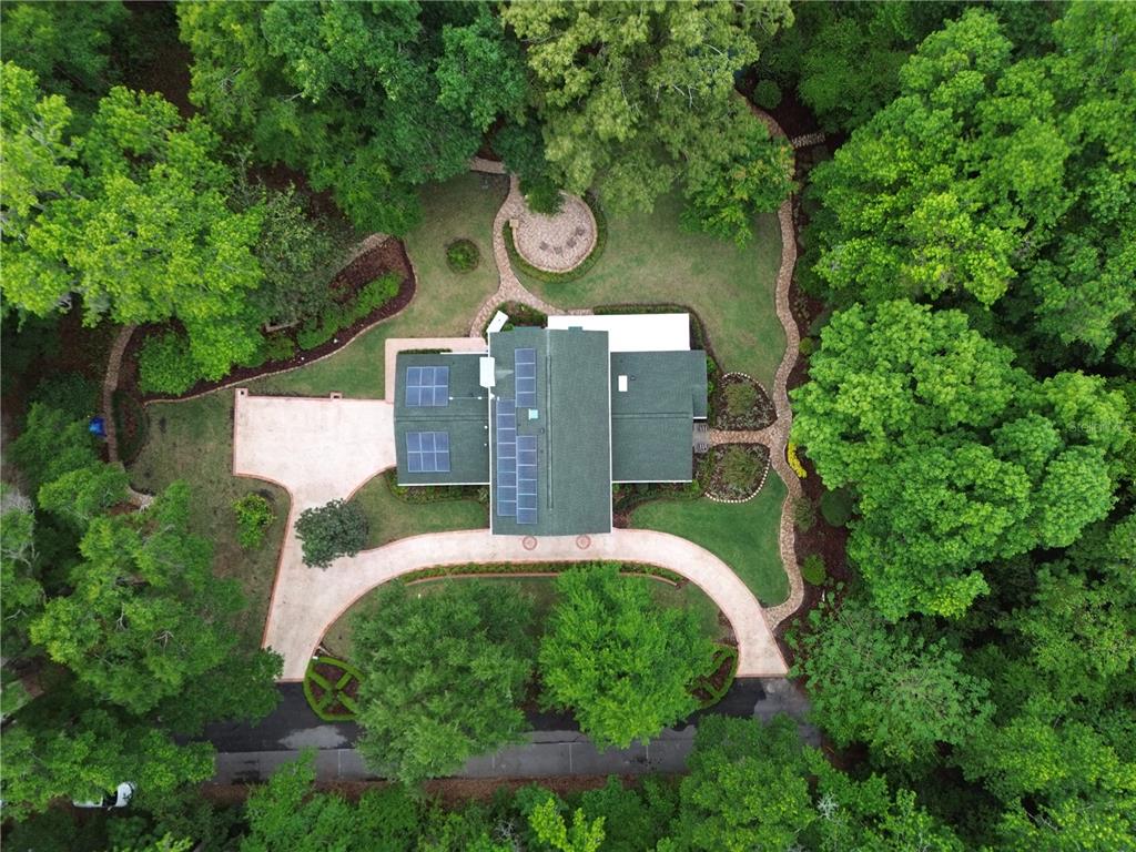 An aerial view shows a house with solar panels surrounded by trees and paved walkways — 2006 NW 23RD STREET, GAINESVILLE, FL