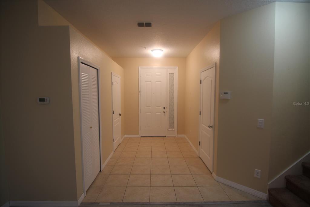 An entryway features beige tile flooring, light-colored walls, a white front door, and three doors — 733 FORTANINI CIRCLE, OCOEE, FL